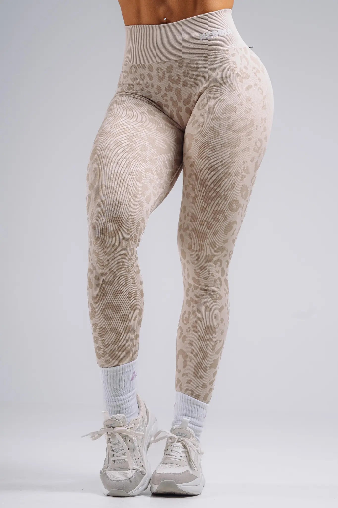 Beige leopard print leggings worn by a person on a gray background